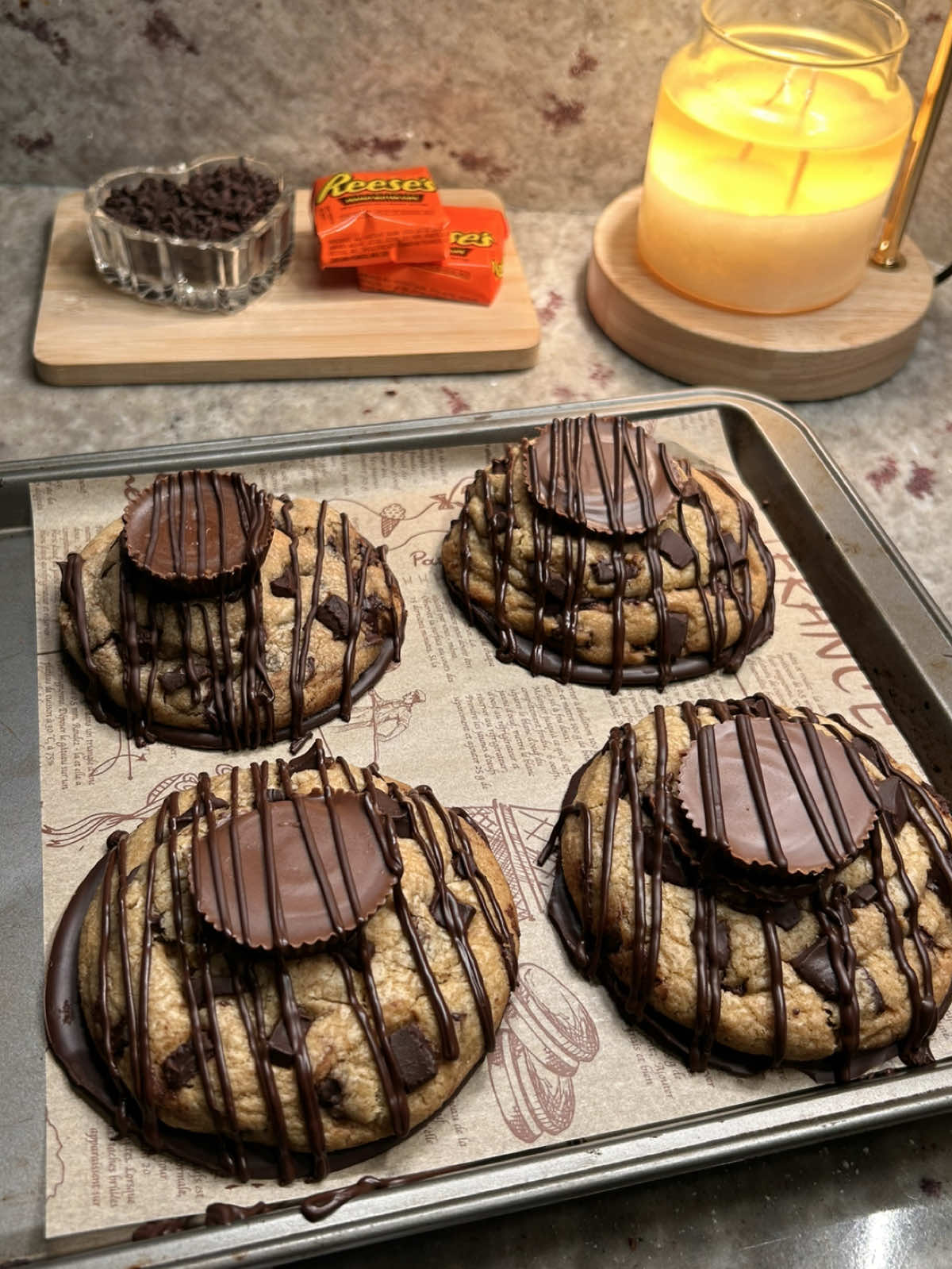 reese’s stuffed dark chocolate chip cookies 🤎🍪 one of my fav cookies omg  recipe: ¾ cup browned salted butter (170g) ¾ cup brown sugar (150g) ¼ cup granulated sugar (50g) 1 large egg 1 tbsp heavy cream (15g) 1 tsp vanilla (5g) 2 cups all-purpose flour (240g) 2 tbsp cornstarch (16g) ½ tsp baking soda (3g) ¼ tsp salt (1.5g) dark chocolate chips (measure with your heart) reese’s cups dark chocolate squares for stuffing extra dark chocolate for dipping/drizzling extra reese’s for topping in a bowl whisk together the warm ( not hot ) browned butter, brown sugar, and granulated sugar until glossy. add the egg, heavy cream, and vanilla and whisk until smooth. fold in the flour, cornstarch, baking soda, and salt until just combined. fold in your dark chocolate chips. scoop the cookie dough and flatten slightly. stuff each cookie with a piece of dark chocolate and a reese’s, then seal and shape the dough into tall cone like cookie dough balls. ( this helps keep the cookies thick ) bake at 375f until the edges are golden but the centers are still soft. while the cookies are still warm, shape them for the perfect cookie shape.  let the cookies cool slightly before topping with reese’s so they don’t completely melt. for the chocolate shell, melt dark chocolate and spoon little circles onto parchment paper. place the bottoms of the cookies onto the melted chocolate and place into the freezer until set. drizzle with more dark chocolate & enjoy :)   #reeses #cookies #chocolatechipcookies #Recipe #baking 